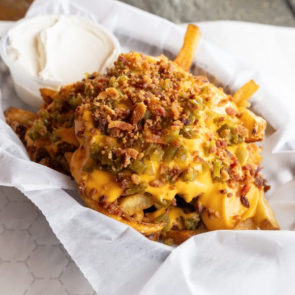 GoldBurgers' loaded fries with melted cheese, jalapeños, bacon bits, and a side of dipping sauce.
